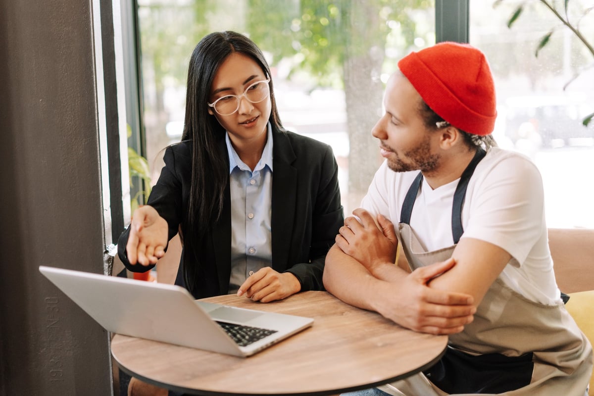 Consultant helping local business owner with laptop